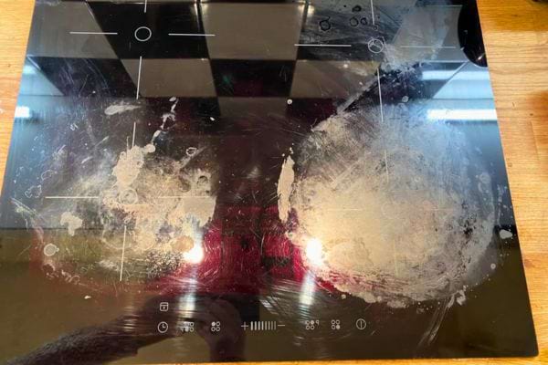 Plaque de cuisson sale avec des traces blanches incrustées.