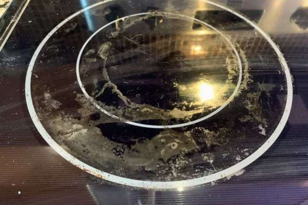 Plaque vitrocéramique très encrassée avec des résidus blancs brûlés.