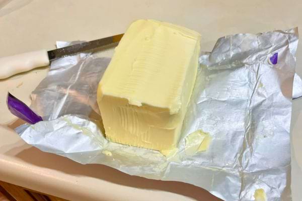 Beurre entamé sur son papier aluminium avec un couteau.