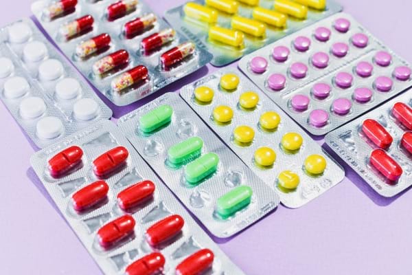 Différentes plaquettes de comprimés colorés alignées sur une table.