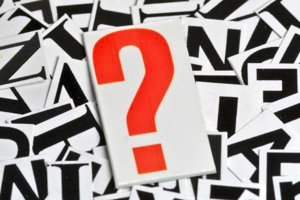 Un point d’interrogation rouge sur fond de lettres en noir et blanc.