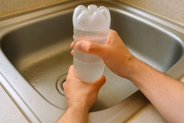 Une bouteille est fortement pressée sur l’évier pour créer une pression.