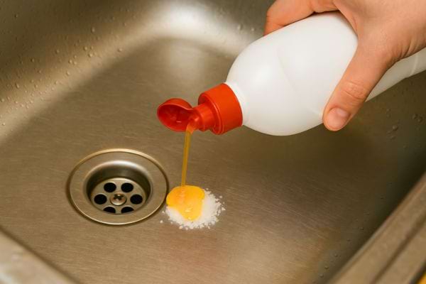 Un produit vaisselle est versé directement sur du sel dans l’évier.