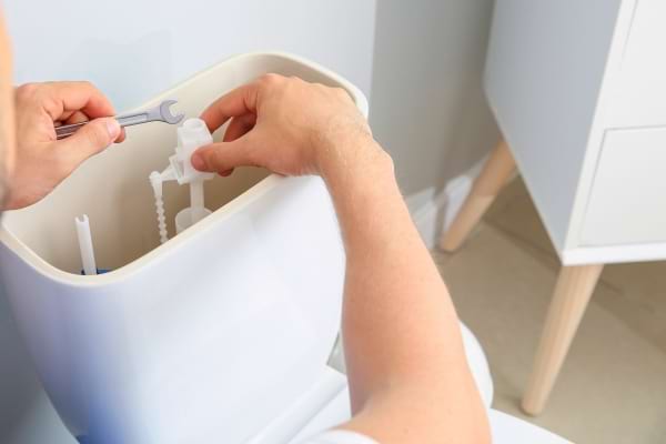 Réparation de mécanisme dans un réservoir de toilettes.