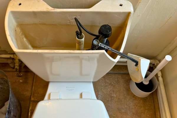 Réservoir de toilettes ouvert montrant l’intérieur entartré.