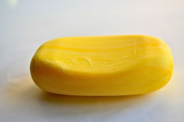 Un savon jaune solide posé sur une surface claire.