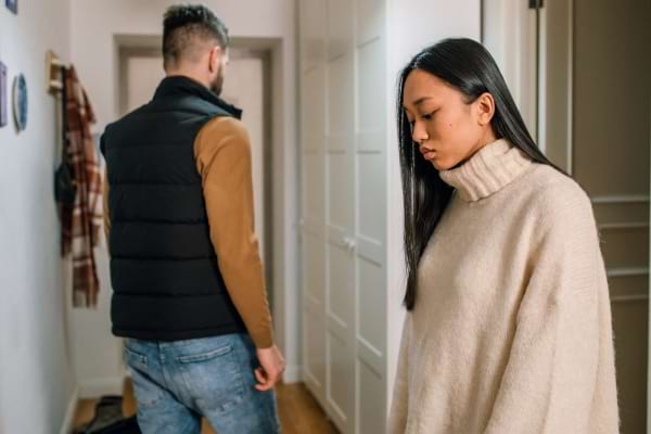Une femme baisse les yeux, l’homme s’éloigne dans un couloir, la tension est palpable.