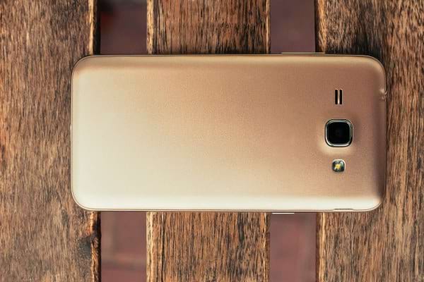 Smartphone doré vu de dos sur surface en bois.