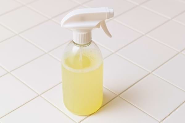 Spray nettoyant jaune sur carrelage blanc.