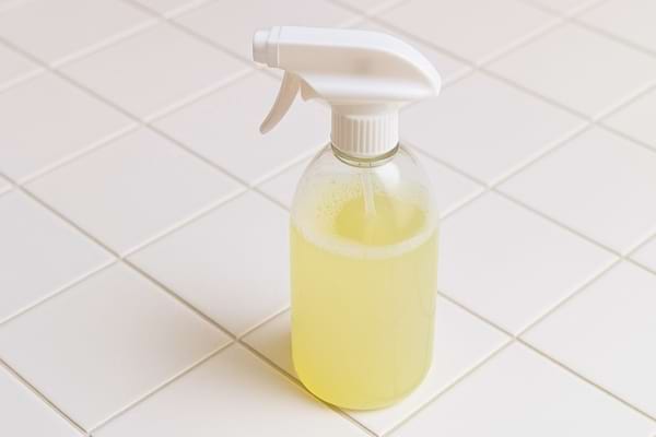Spray nettoyant jaune pos&eacute; sur un carrelage blanc.