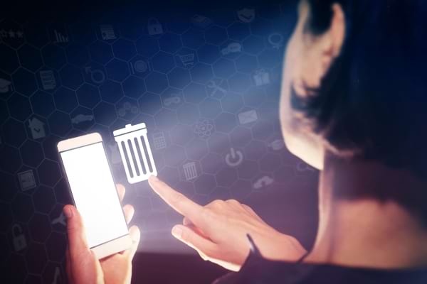Personne supprimant des fichiers sur un smartphone avec une icône de corbeille.