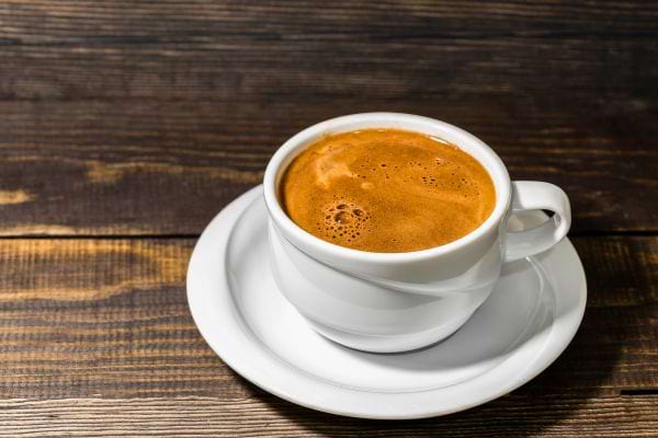 Une tasse de café chaud posée sur une table en bois.