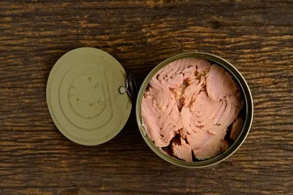 Une conserve de thon est entamée, laissant apparaître les morceaux roses compactés.