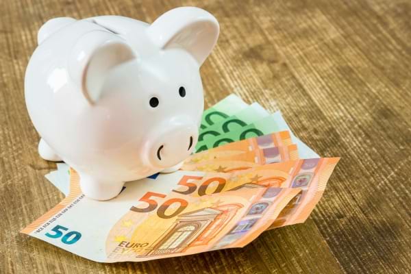 Tirelire blanche posée sur des billets en euros.