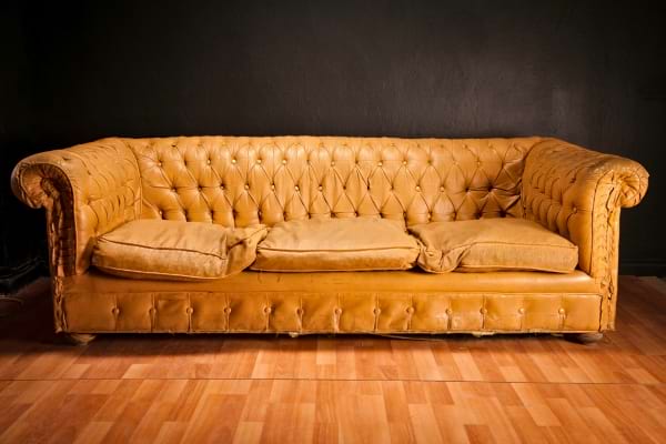 Vieux canapé en cuir usé dans une pièce sombre.  