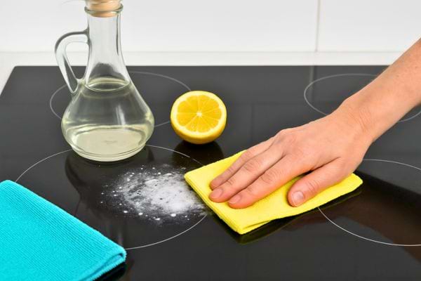 Main utilisant chiffon jaune avec vinaigre, citron et bicarbonate.