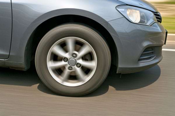 Une voiture grise roule, gros plan sur la roue en mouvement.