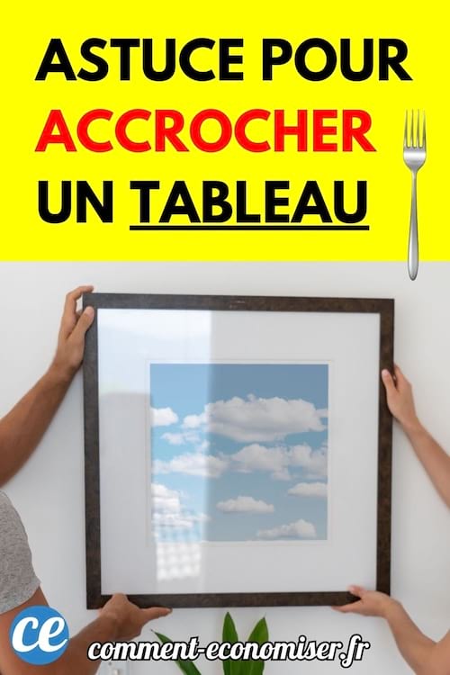 Deux personnes accrochent un grand tableau encadré au mur.