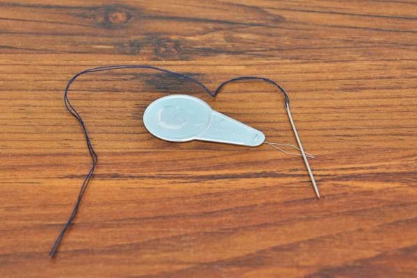 Un passe-fil en métal utilisé pour enfiler un fil sombre dans une aiguille.