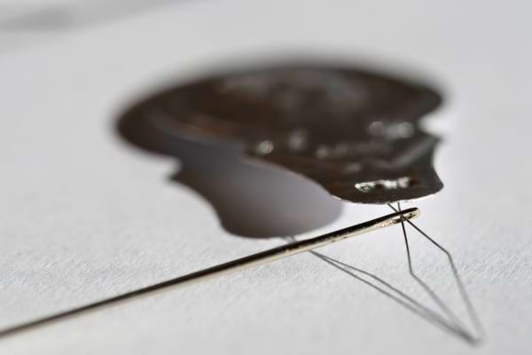 Une aiguille fine traversée par le fil métallique d’un passe-fil.