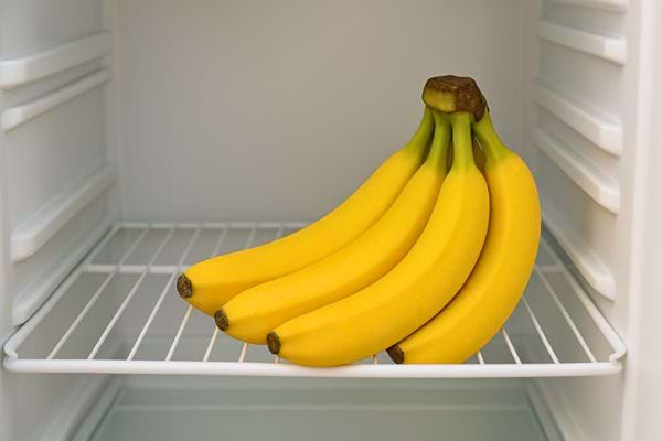 Un régime de bananes fraîches posé directement sur l’étagère d’un frigo.