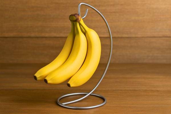 Un régime de bananes suspendu sur un support métallique élégant.