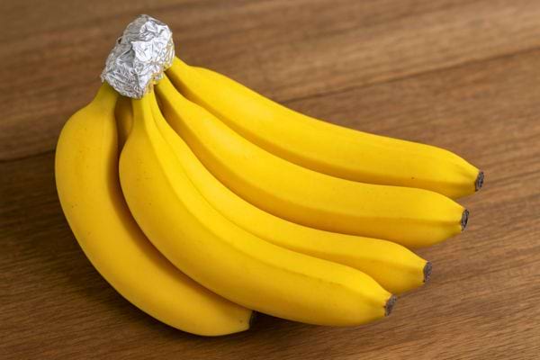 Un régime de bananes dont la tige est recouverte de papier aluminium.