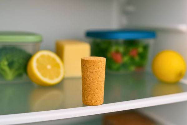 Un bouchon de liège est visible dans le frigo parmi différents aliments.