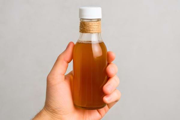 Main tenant une petite bouteille de vinaigre de cidre.