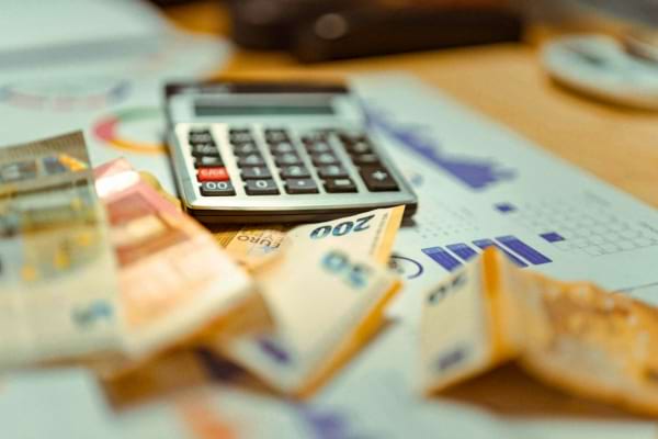 Une calculatrice et des billets d’euros étalés sur des graphiques.