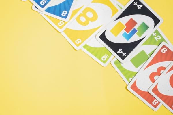 Plusieurs cartes Uno de couleurs vives sont étalées sur un fond jaune.