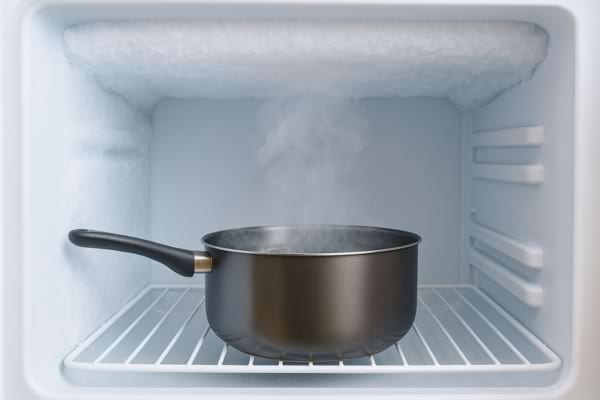 Une casserole d’eau chaude dégage de la vapeur à l’intérieur d’un congélateur givré.