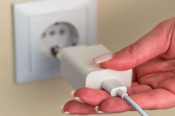 Un chargeur de téléphone branché dans une prise murale blanche.