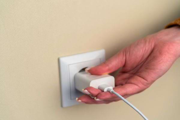 Un chargeur de téléphone en train d’être débranché d’une prise.