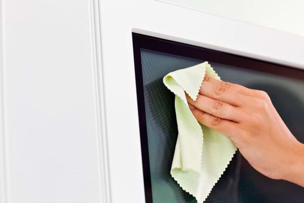 Un chiffon doux essuie un écran de télévision noir.