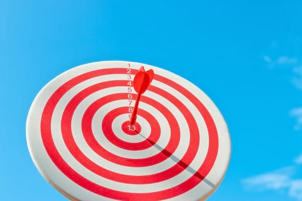 Une cible rouge et blanche avec une flèche plantée au centre.
