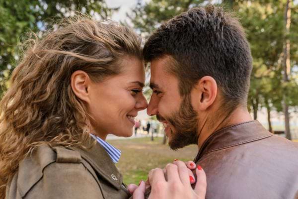 Deux amoureux se regardent avec tendresse, nez contre nez, dans un parc.