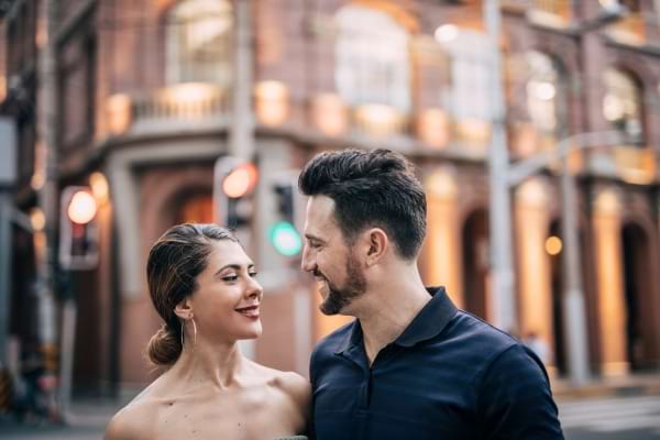 Un couple s’échange un regard complice en souriant dans la rue.