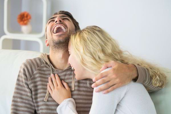 Un couple rit aux éclats en partageant un moment complice.