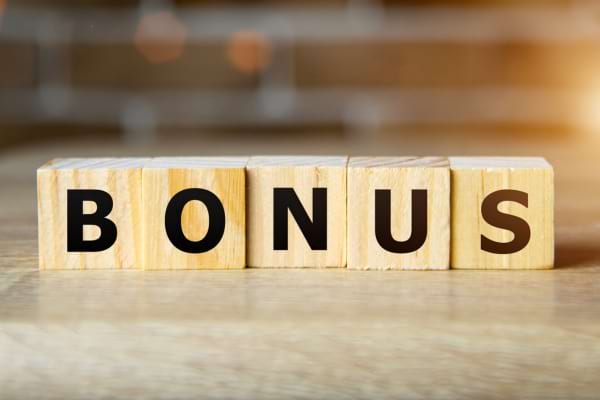 Des cubes en bois affichent le mot "BONUS" posé sur une table claire.