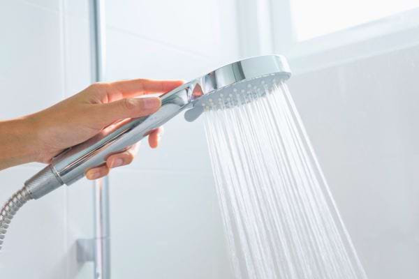 Main tenant un pommeau de douche avec de l’eau qui coule.