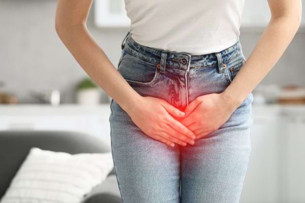 Une femme tient son bas-ventre avec douleur, mise en évidence par une lueur rouge.