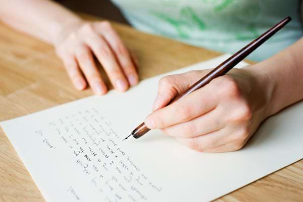 Une personne écrit une lettre manuscrite.
