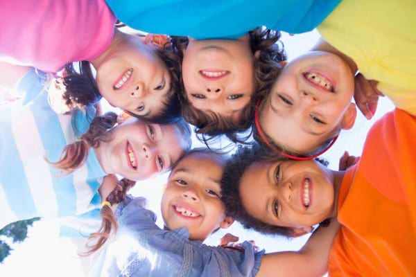 Groupe d’enfants souriants formant un cercle et regardant vers la caméra.