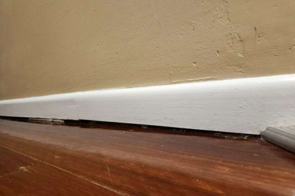 Plinthe blanche laissant appara&icirc;tre un espace vide en bas du mur.