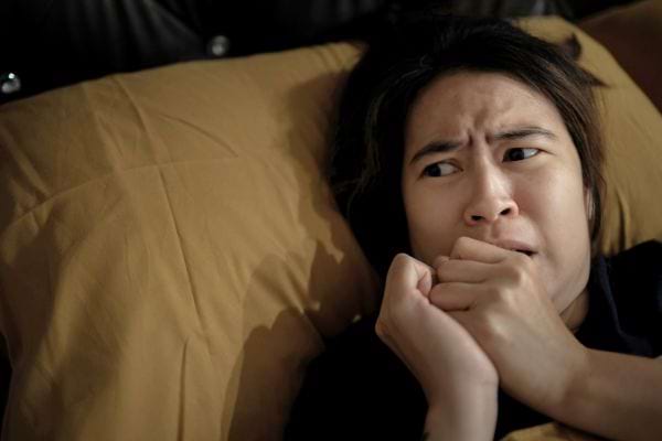 Une femme allongée, les yeux écarquillés, visiblement effrayée.