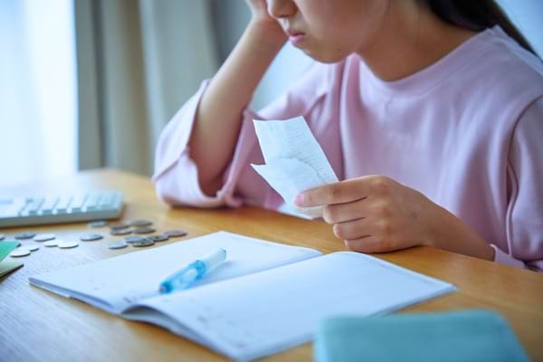 Une femme vérifie ses comptes avec des pièces et un carnet.