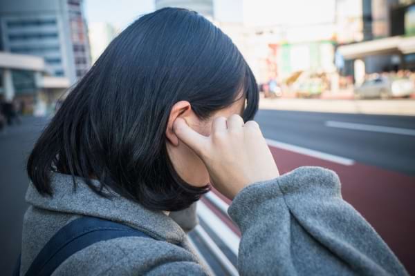 Une femme se bouche les oreilles en marchant dans la rue.