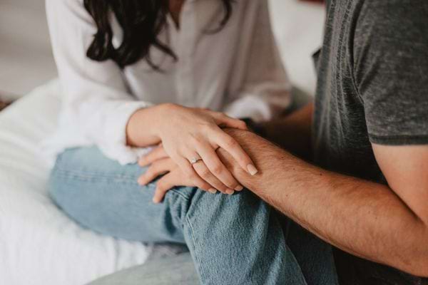 Une femme pose sa main sur le genou d’un homme assis.