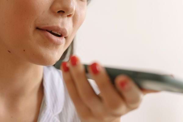 Une femme parle en tenant son téléphone près de sa bouche.